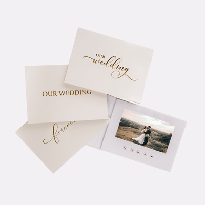 A set of three video books with a white and beige linen cover. The books are labeled 'Our Wedding' and have a picture of a couple on one of the covers.